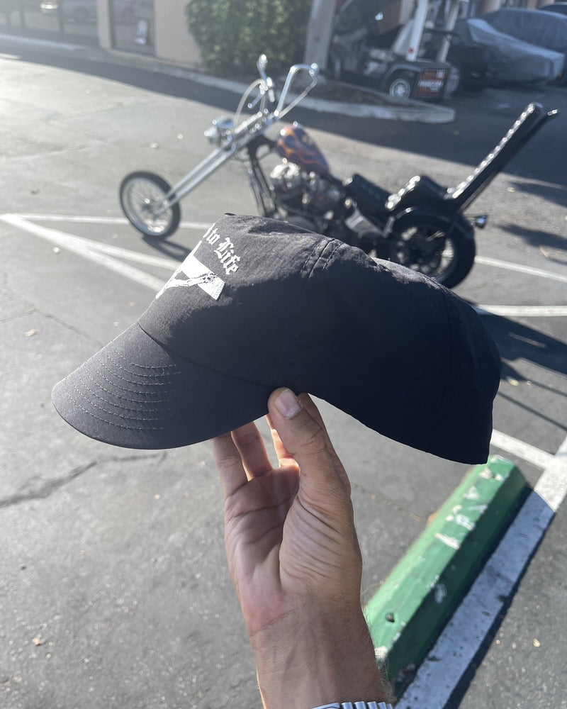 Crucified to Life hat held in front of a motorcycle