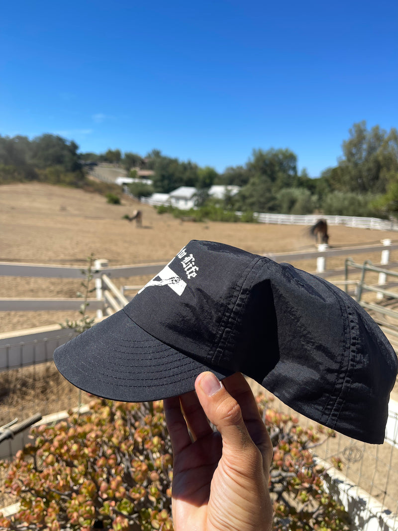 Hand holding the Crucified to Life hat outdoors, brim bent